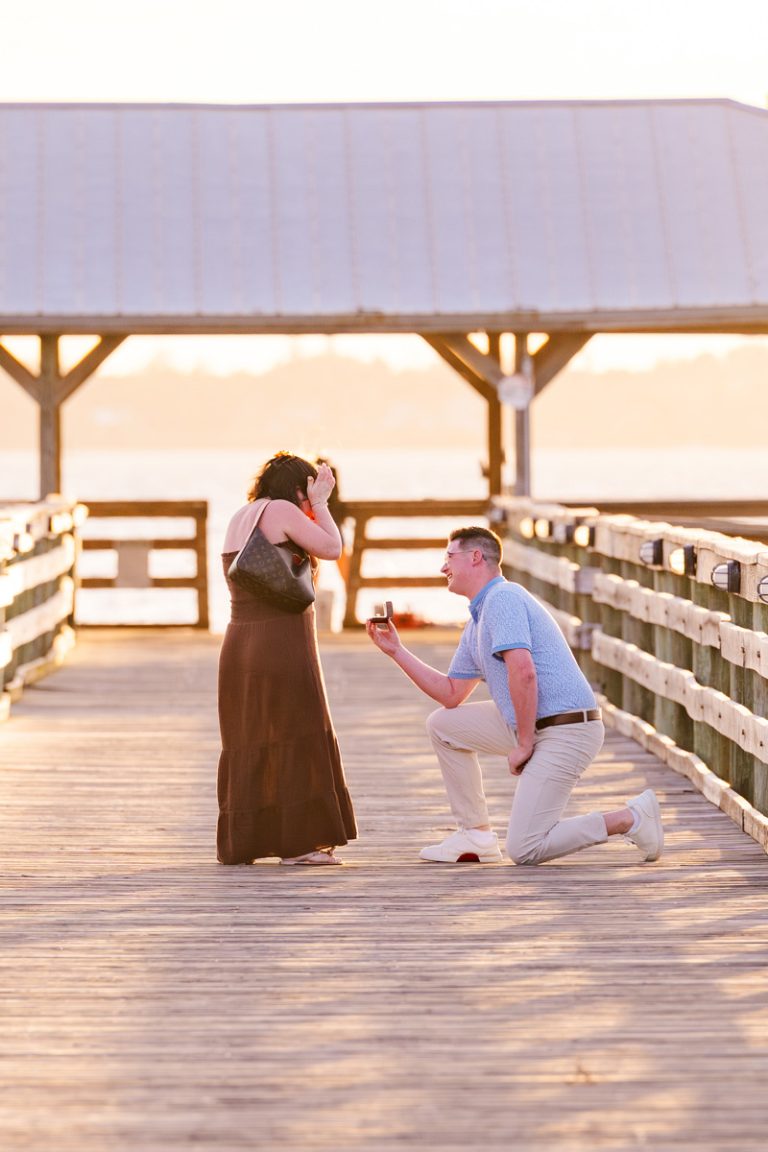 Women in red dress on the pier at Rykeman park getting proposed to
