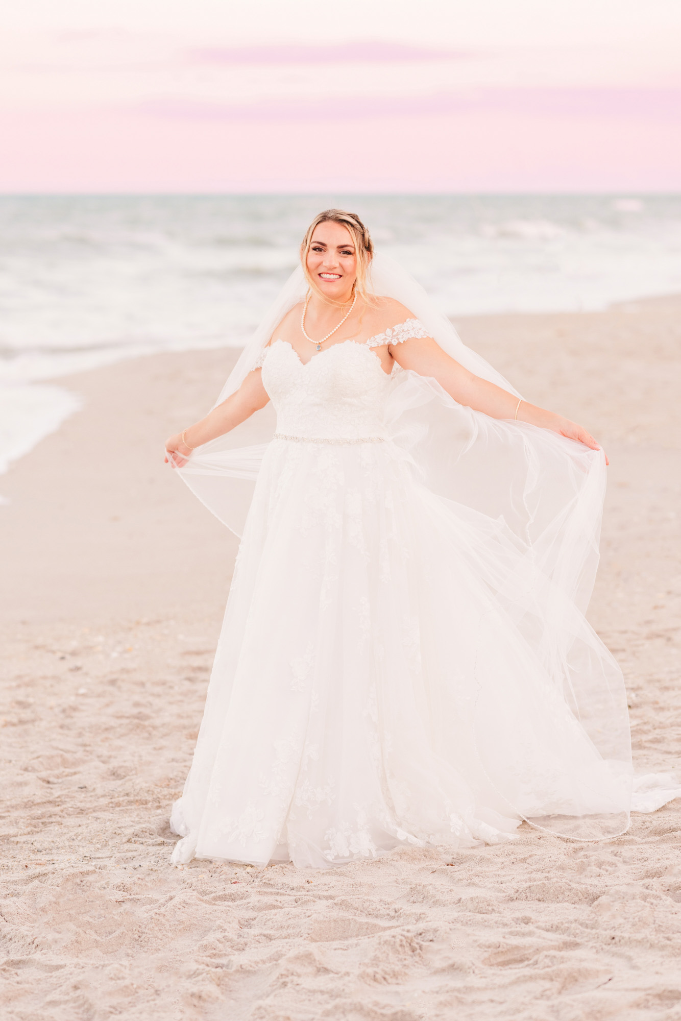 bride playing with her veil on the beach