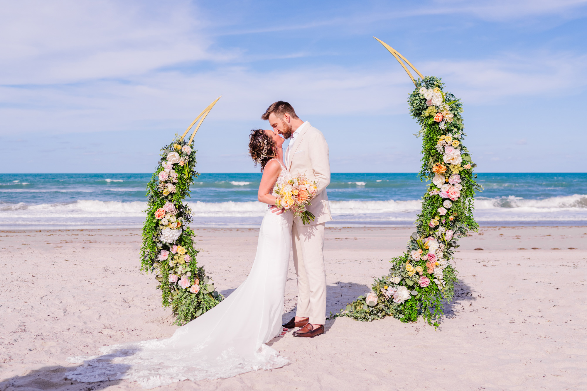 Couple kissing under their wedding arch on Melbourne Beach