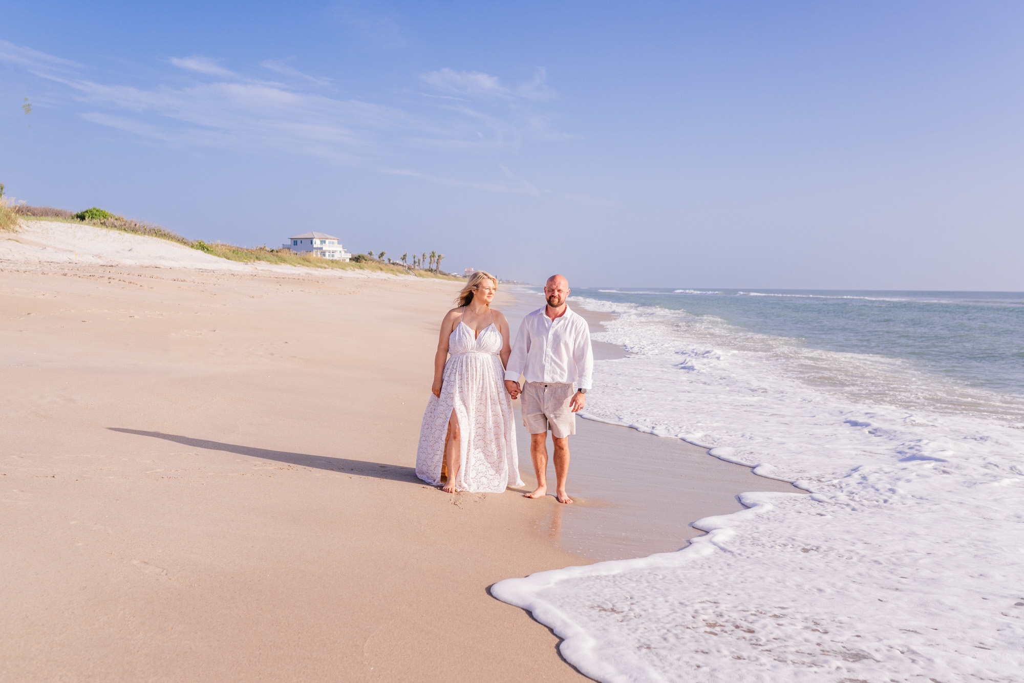 Couple holding hands and walking along beach after sunrise Melbourne Beach wedding
