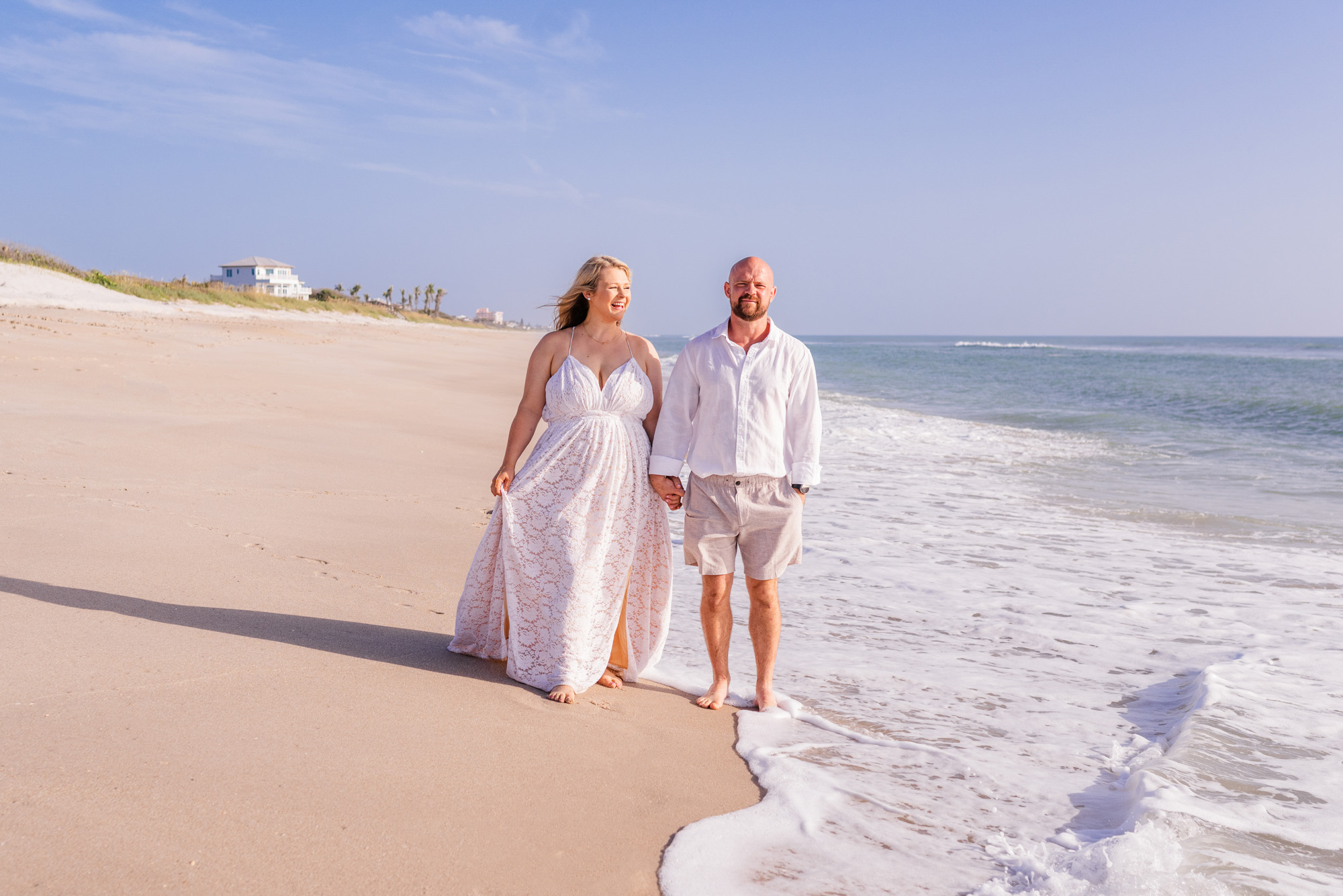 Couple walking along beach after their sunrise wedding