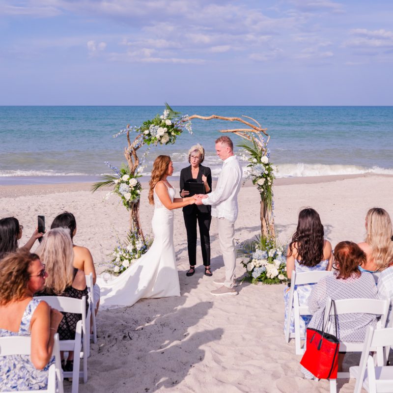 wide shot of bride and groom at their wedding ceremony on the beach with the ocean in the background