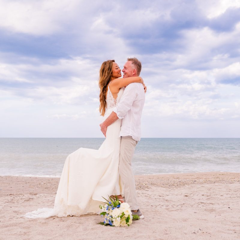 Groom lifting bride into the air on Melbourne beach after their wedding