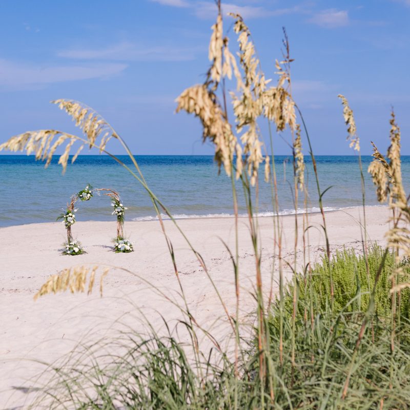 view of the wedding arch seen through sea oats on Melbourne Beach