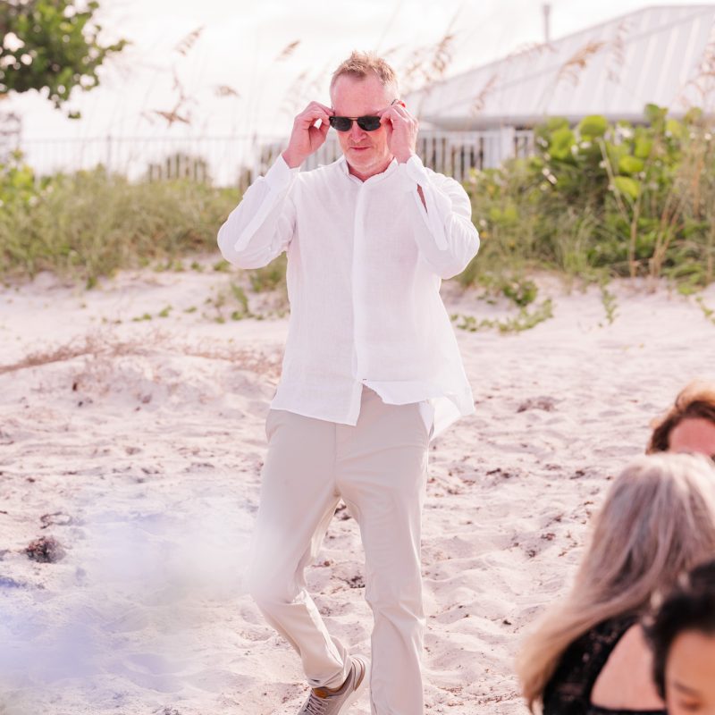 groom walking down the aisle while adjusting his sunglasses