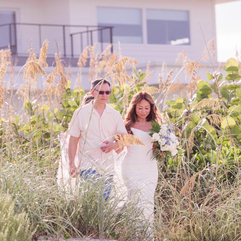 Bride walking down the dunes to the ceremony at her Melbourne Beach wedding