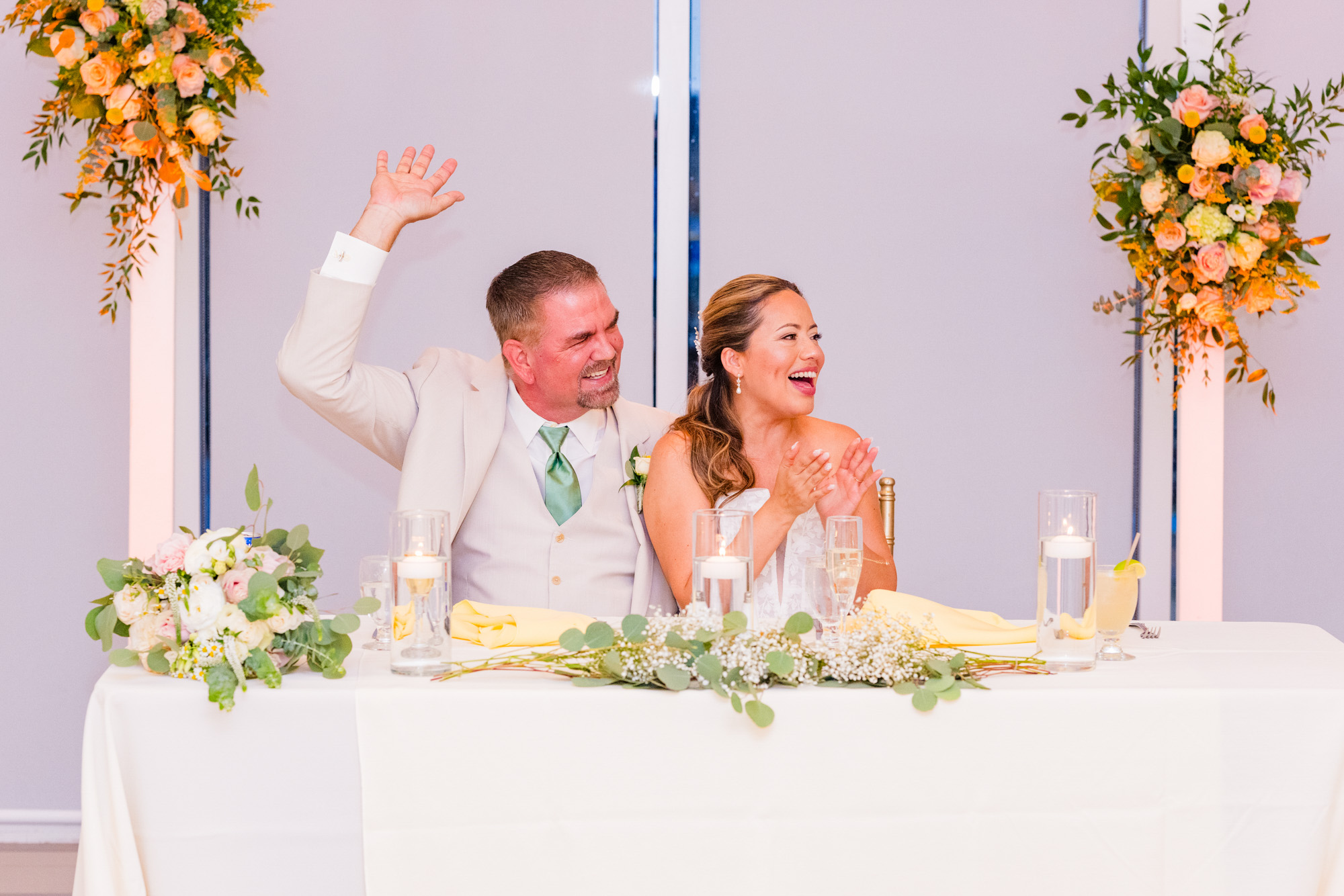 Bride and groom sitting at head table cheering
