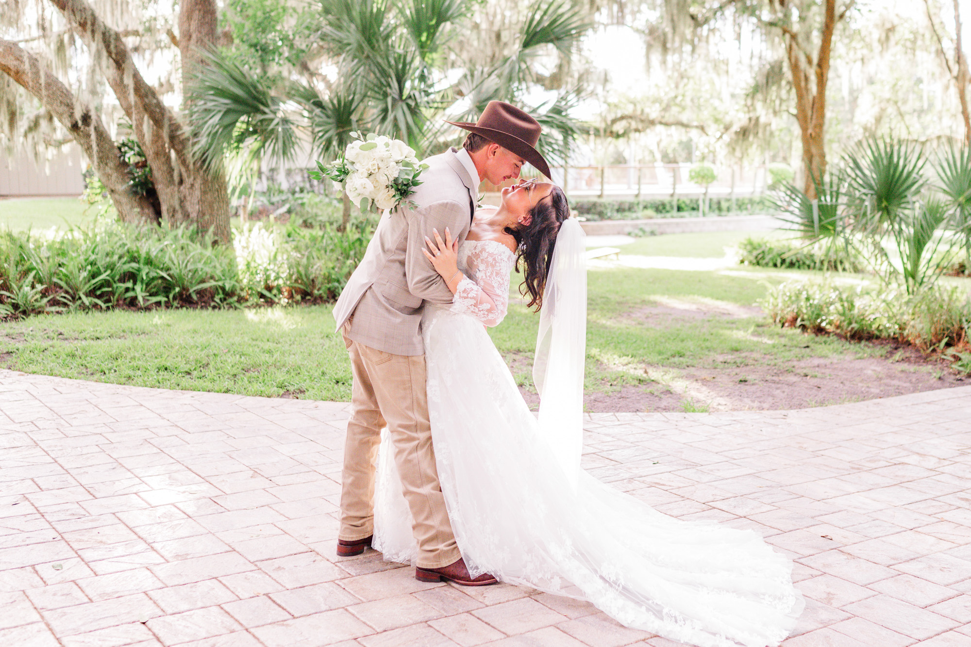 Man in a cowboy hat dipping his bride at Up The Creek Farms wedding