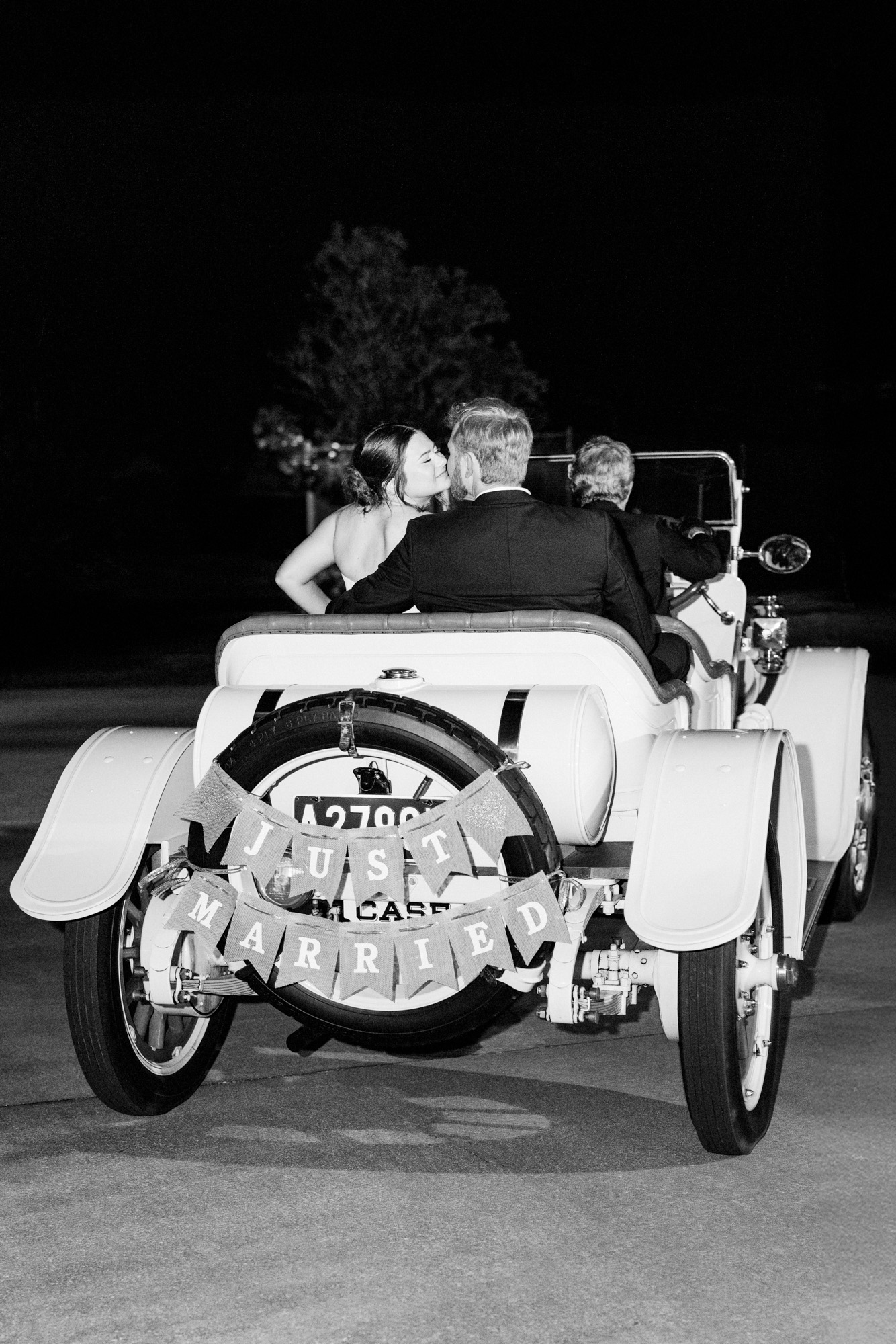 black and white of bride and groom kissing in the getaway antique car at their Melbourne, Florida Suntree Country Club wedding