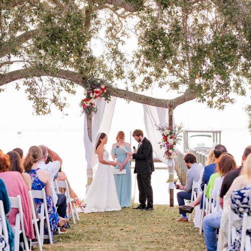 Wedding ceremony under trees on th edge of the Indian River Lagoon in Melbourne Beach, Florida