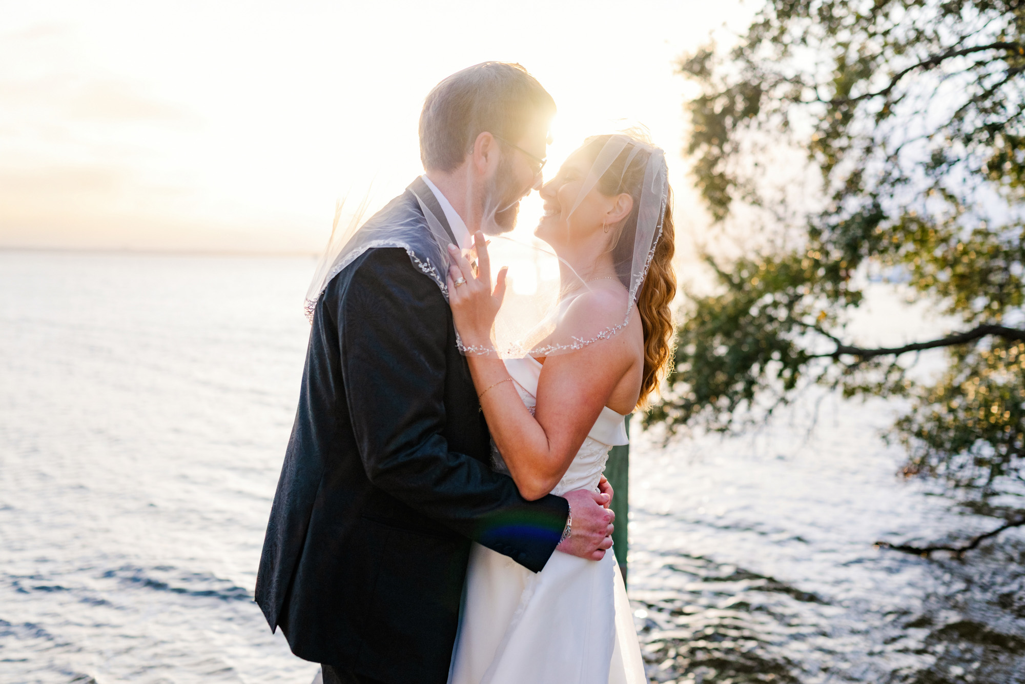 bride and groom under a veil with the sun setting behind them in Melbourne Beach, Florida