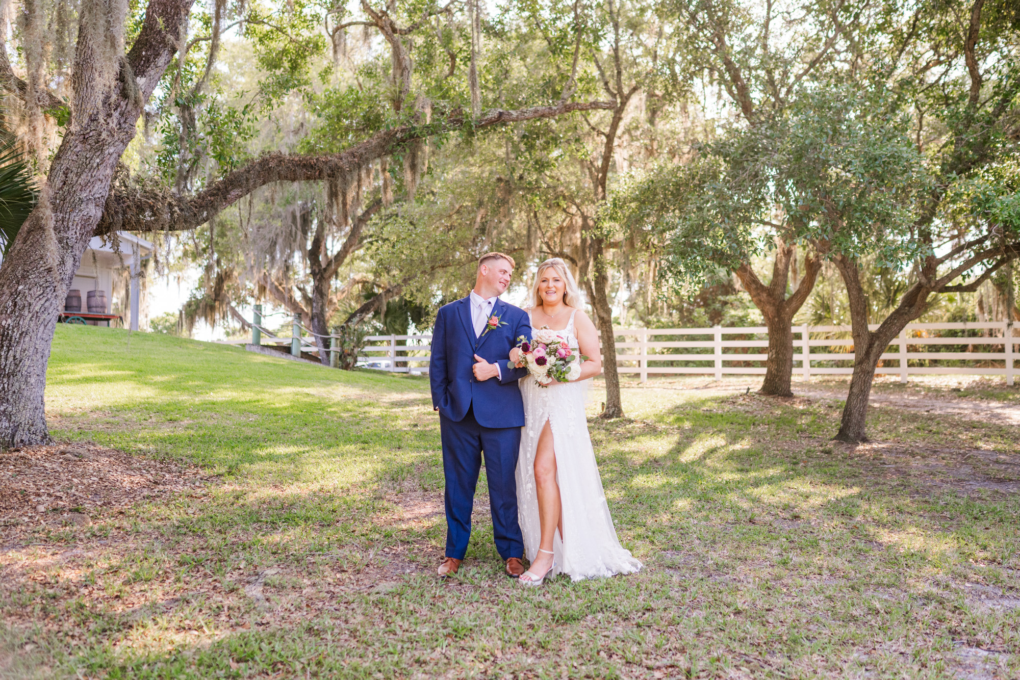 Couple linking arms under the oak trees at their Up the Creek Farms wedding