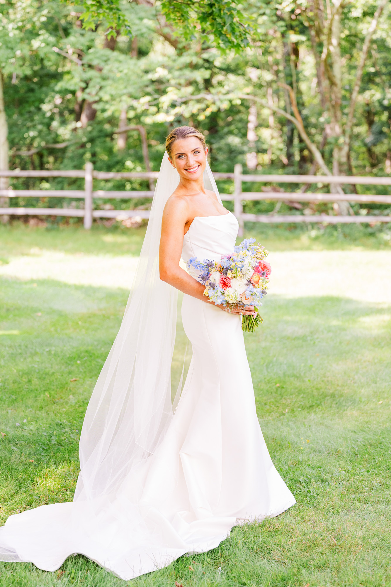 Bride in a white wedding gown holding a colorful bouquet at a summer wedding in Pawling, New York