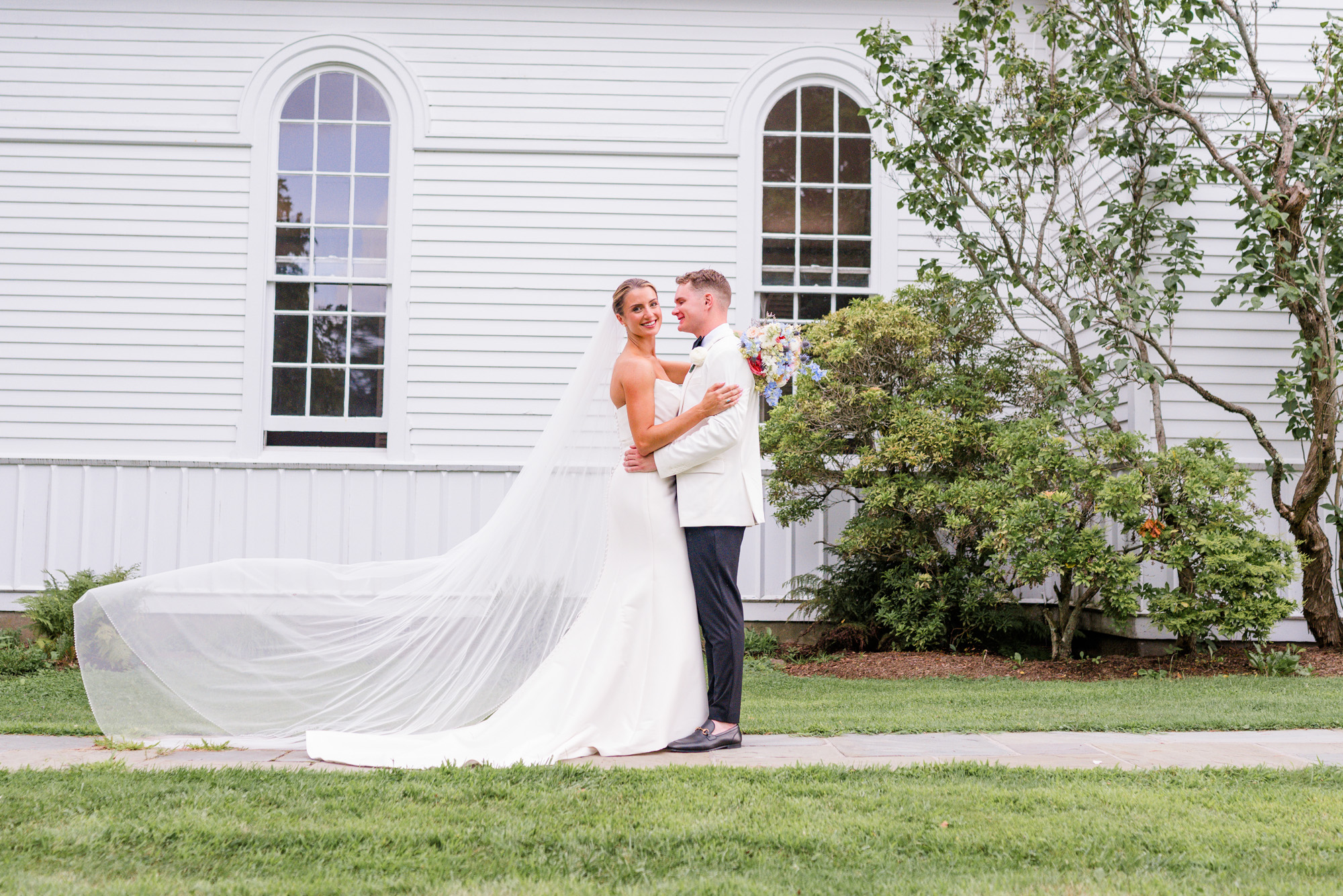 Bride and groom posing together outside Christ Church on Quaker Hill in Pawling