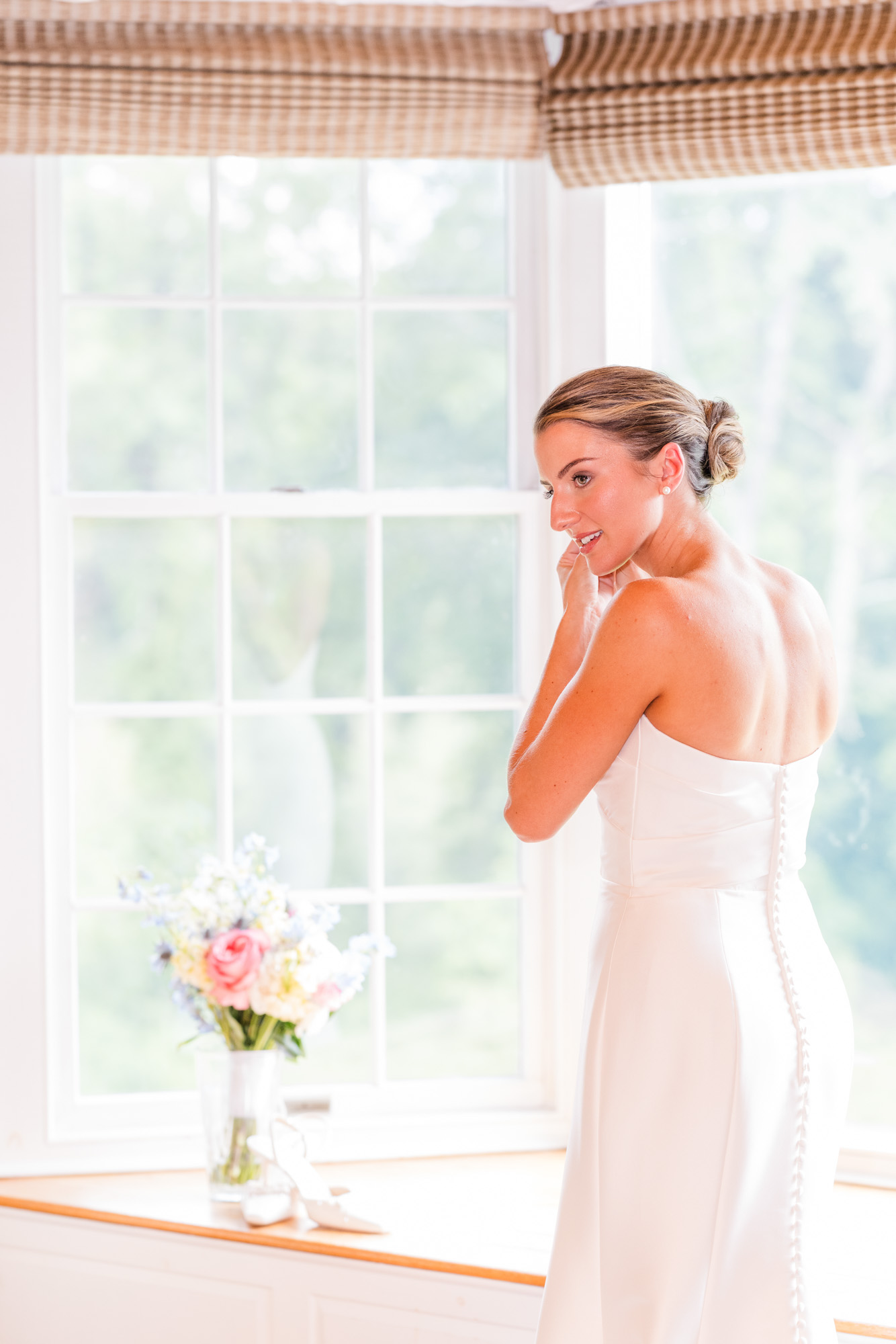 Bride getting ready beside a large window before her Pawling New York wedding