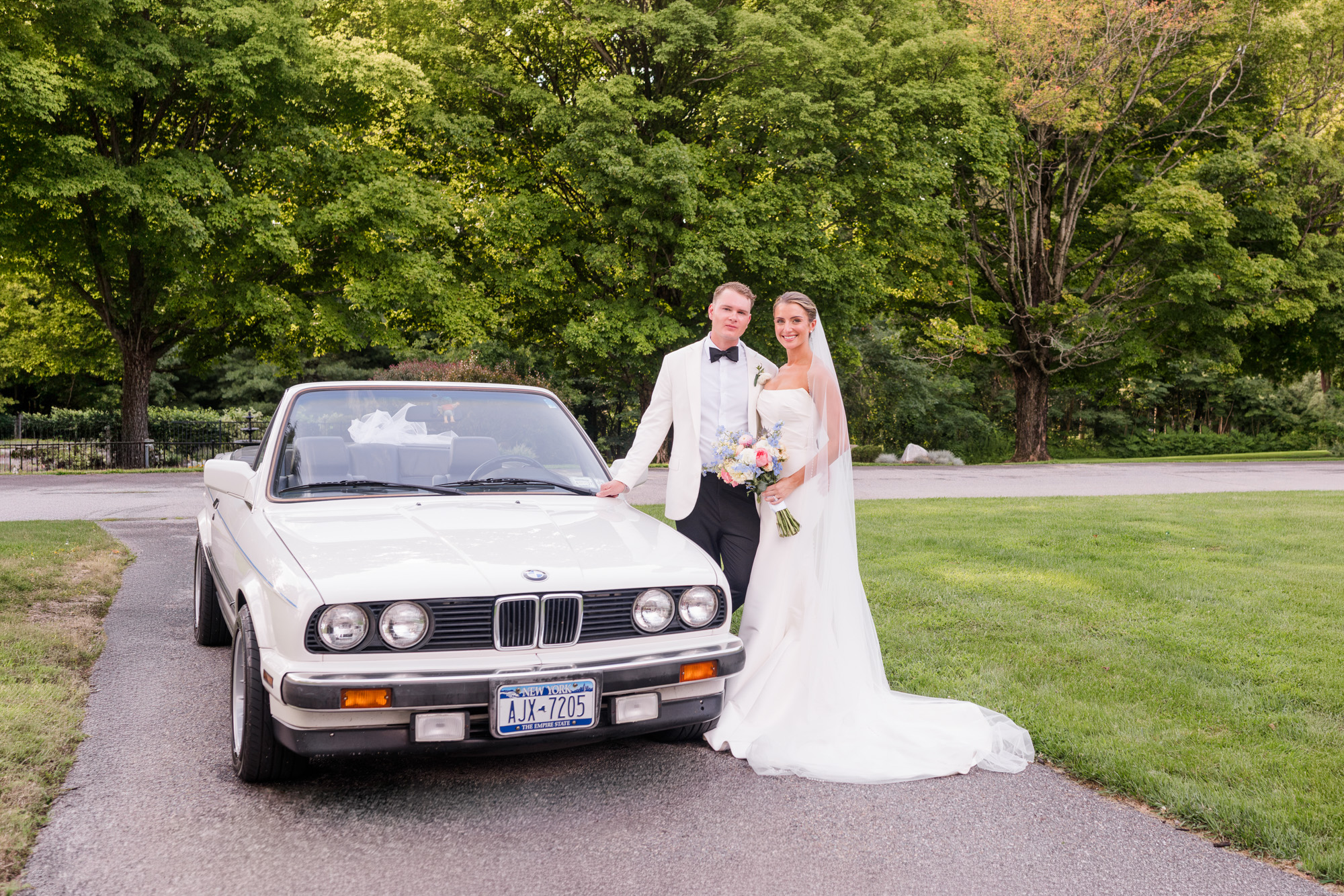 Bride and groom posing with a vintage white BMW at their Pawling New York wedding
