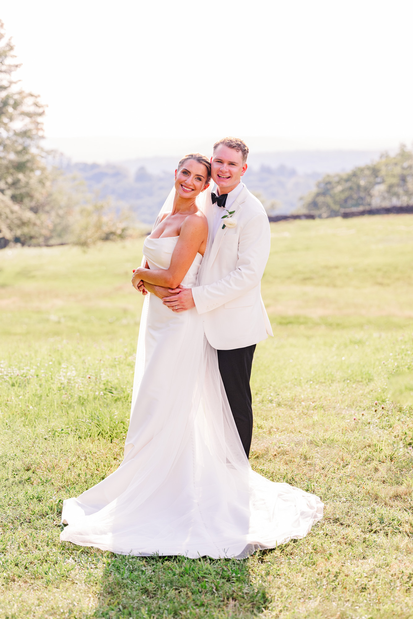 Newlyweds embracing in warm evening light during their summer Pawling wedding