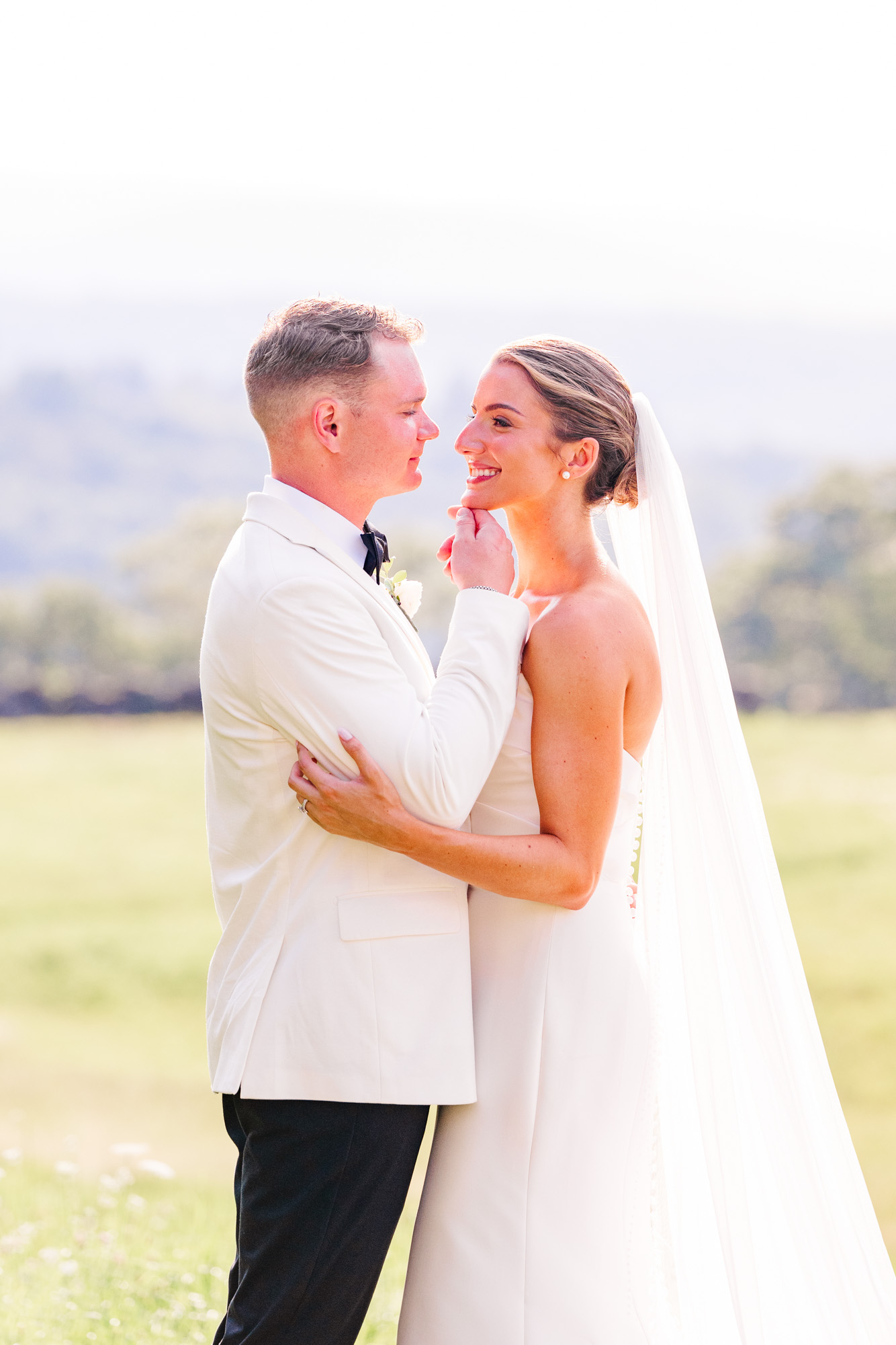 Bride and groom sharing a romantic moment in a sunlit field in Pawling New York