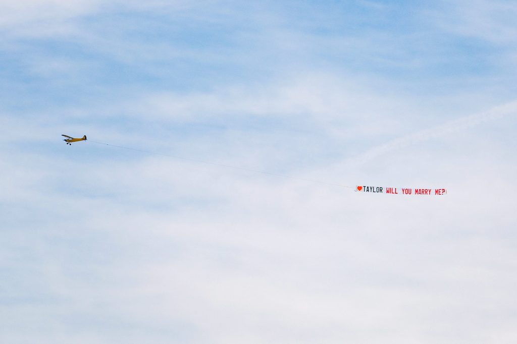 plane is sky over Melbourne Beach carrying a banner saying will you marry me?