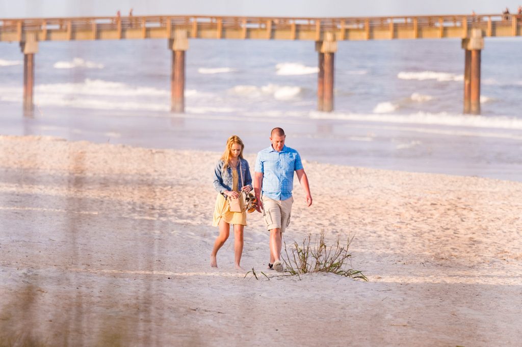 Man and women walking on beach up to the spot where he is going to propose