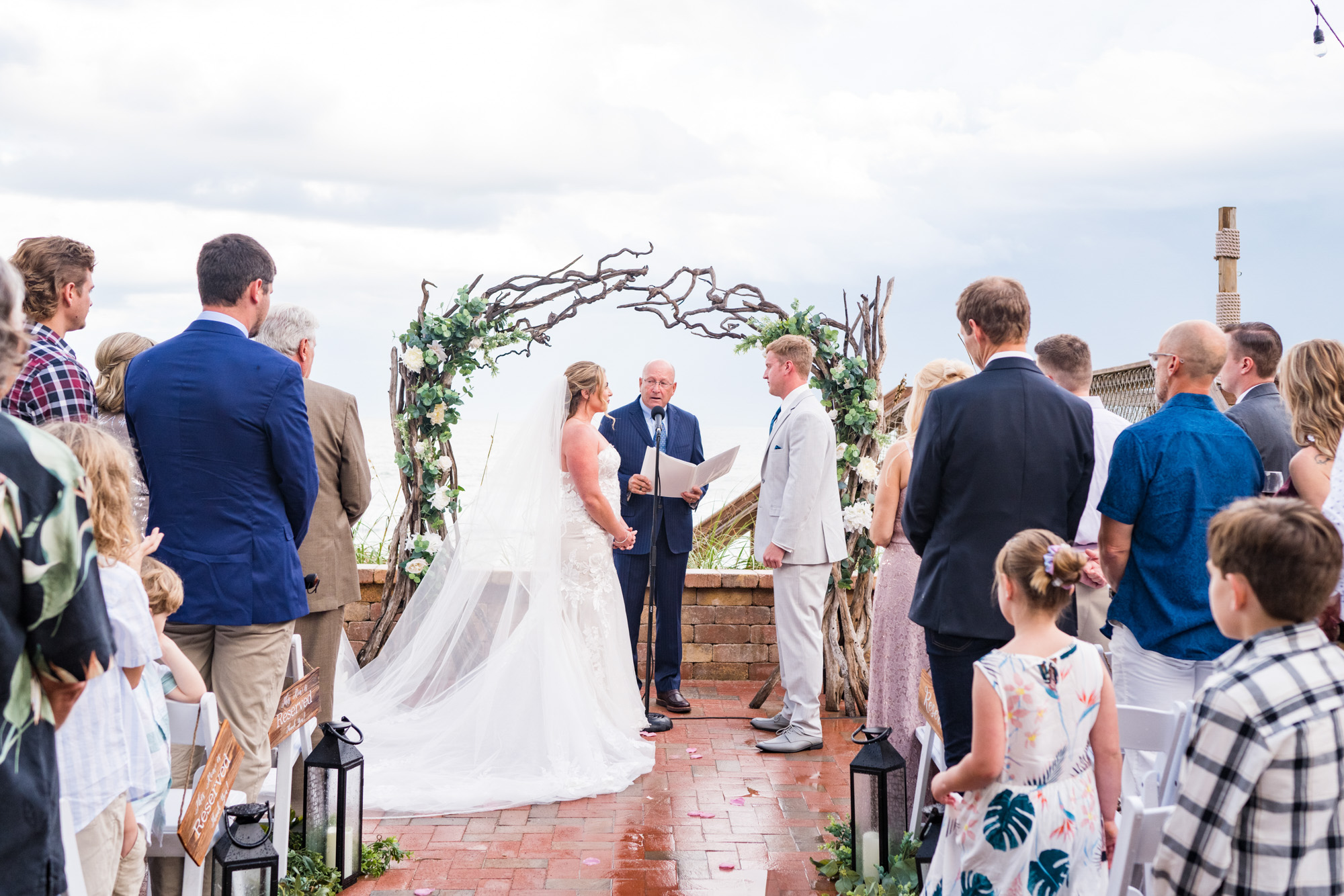 Wedding ceremony held outdoors after rain, with the couple standing beneath a rustic branch arch in Vero Beach.
