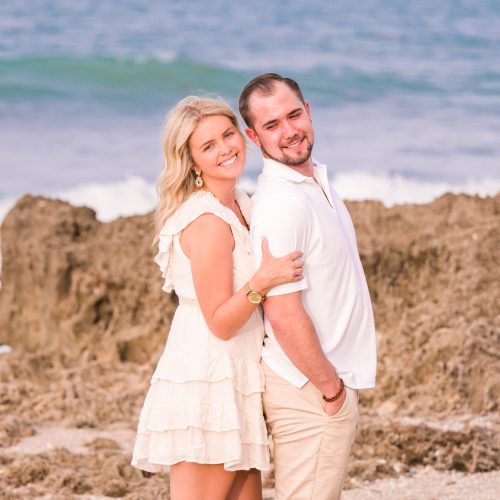 Couple in white and tan hugging on the beach in Jupiter, Florida