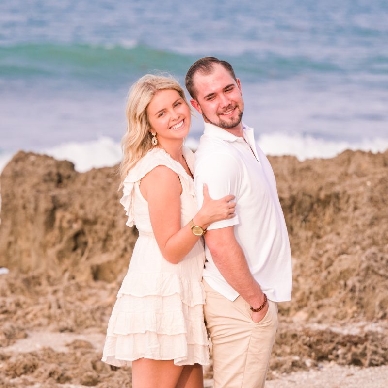 Couple in white and tan hugging on the beach in Jupiter, Florida