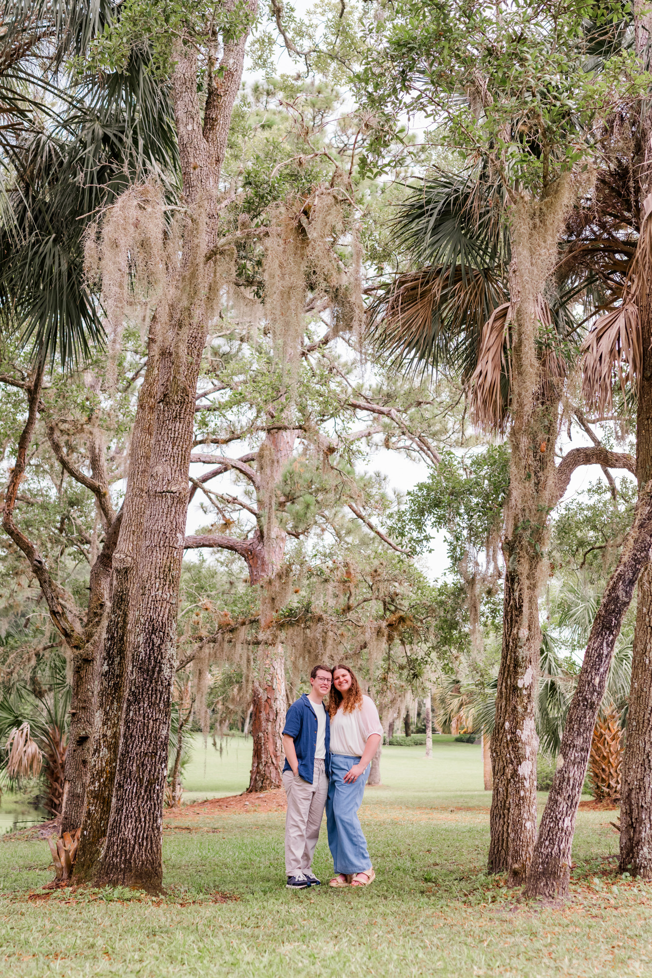 Couple standing between tall oak trees at their Up the Creek Farms engagement session