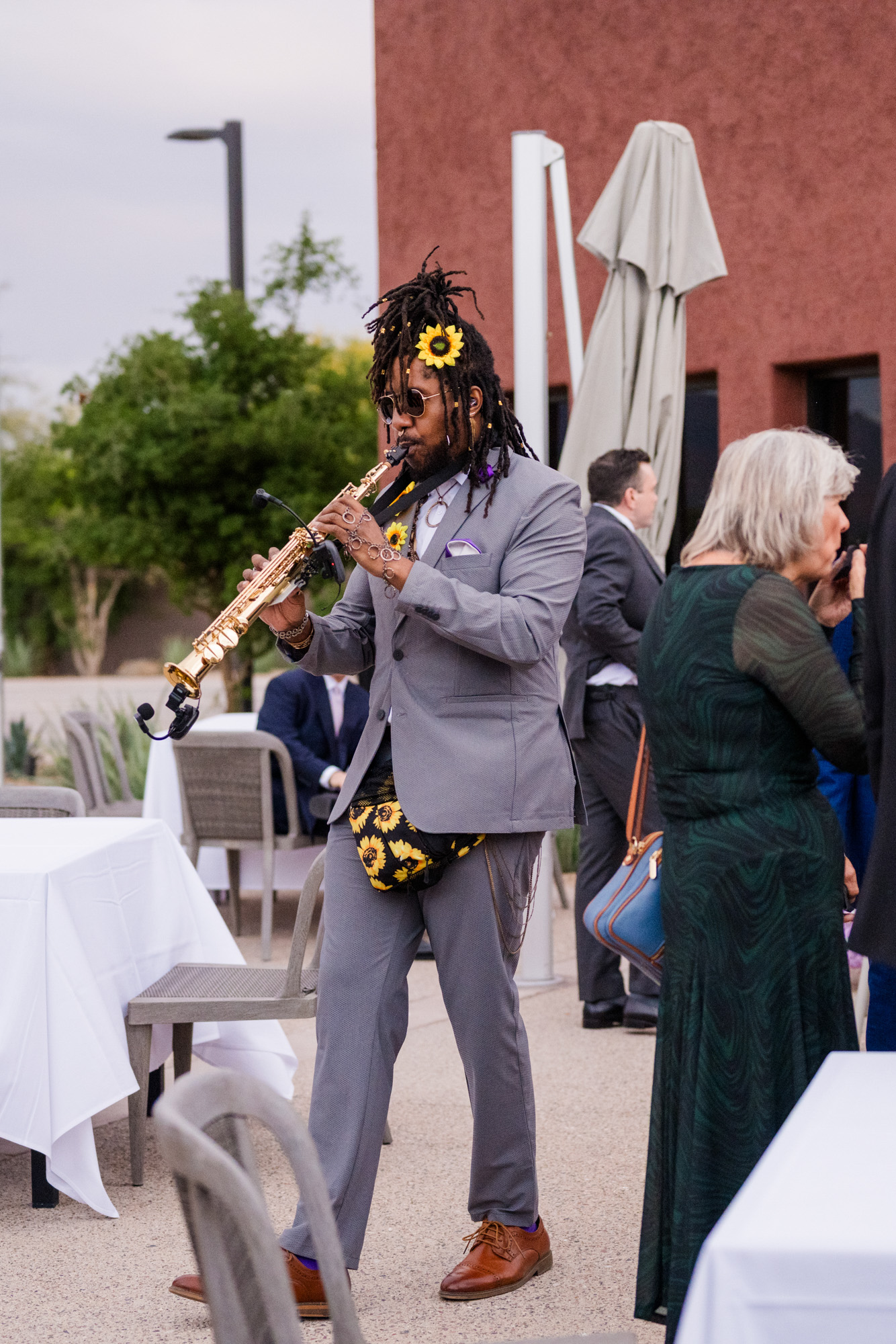 Musician playing saxophone during an outdoor wedding reception.