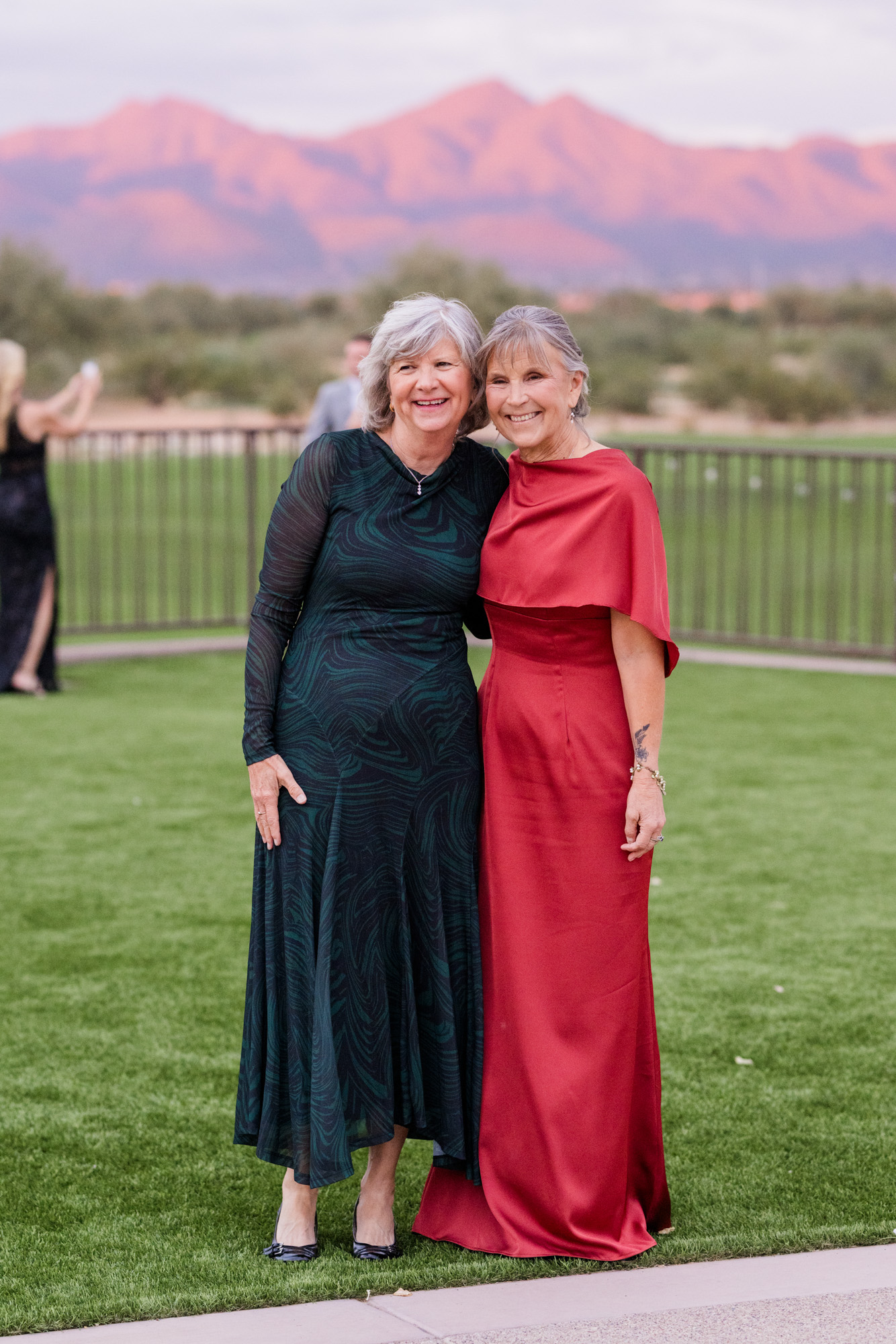 Wedding guests posing together outdoors with mountains glowing in the distance.