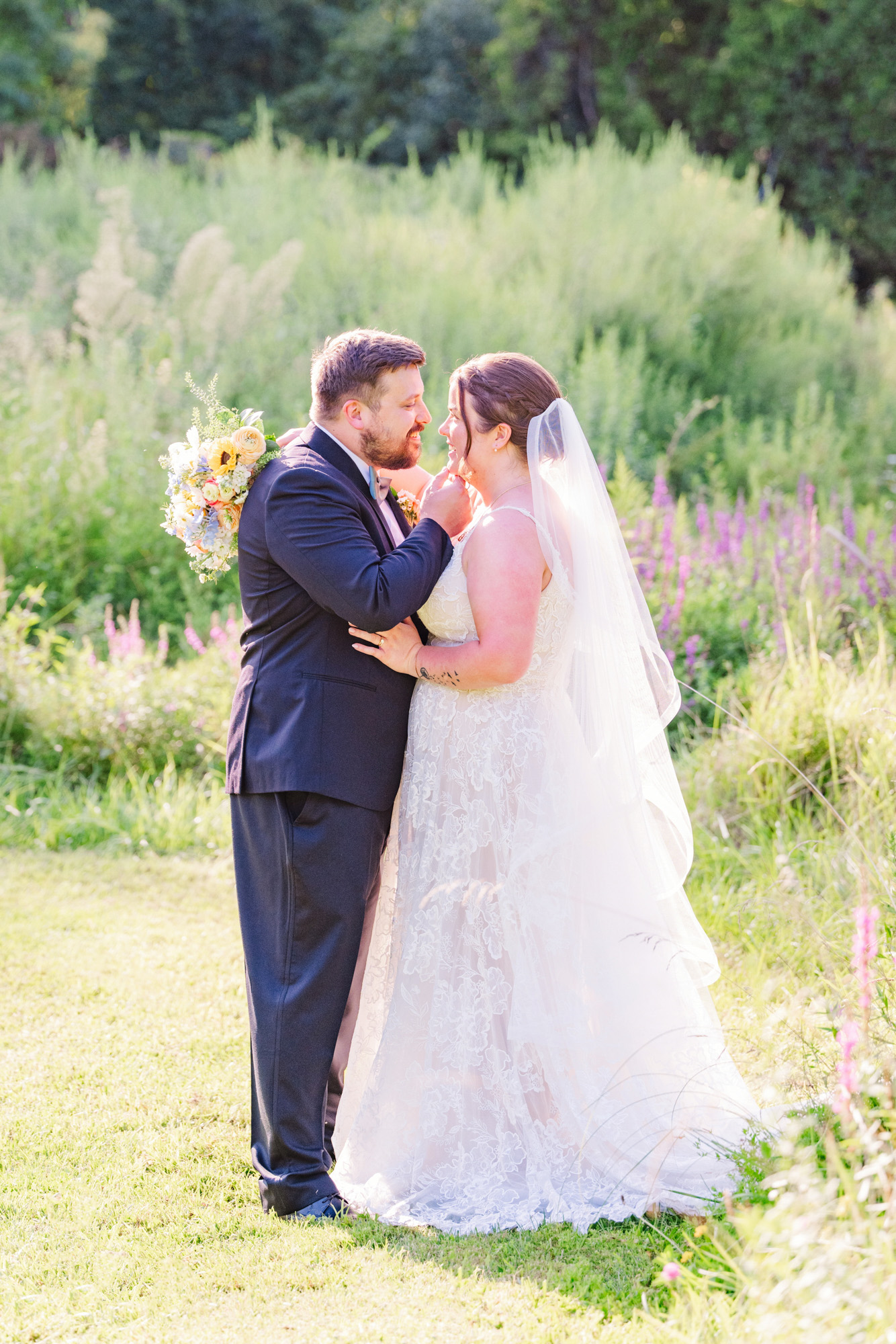 Bride and groom laughing together among wildflowers during golden-hour wedding portraits.