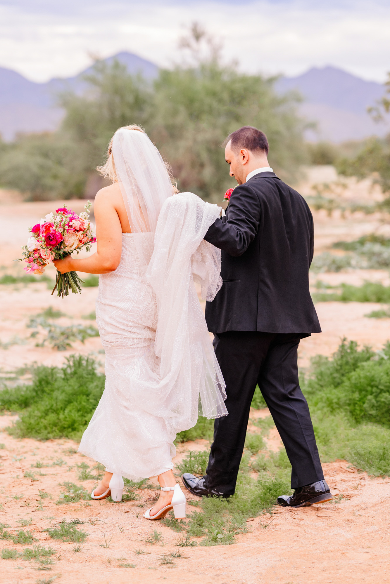 Bride and groom walking together outdoors with mountain views in the distance