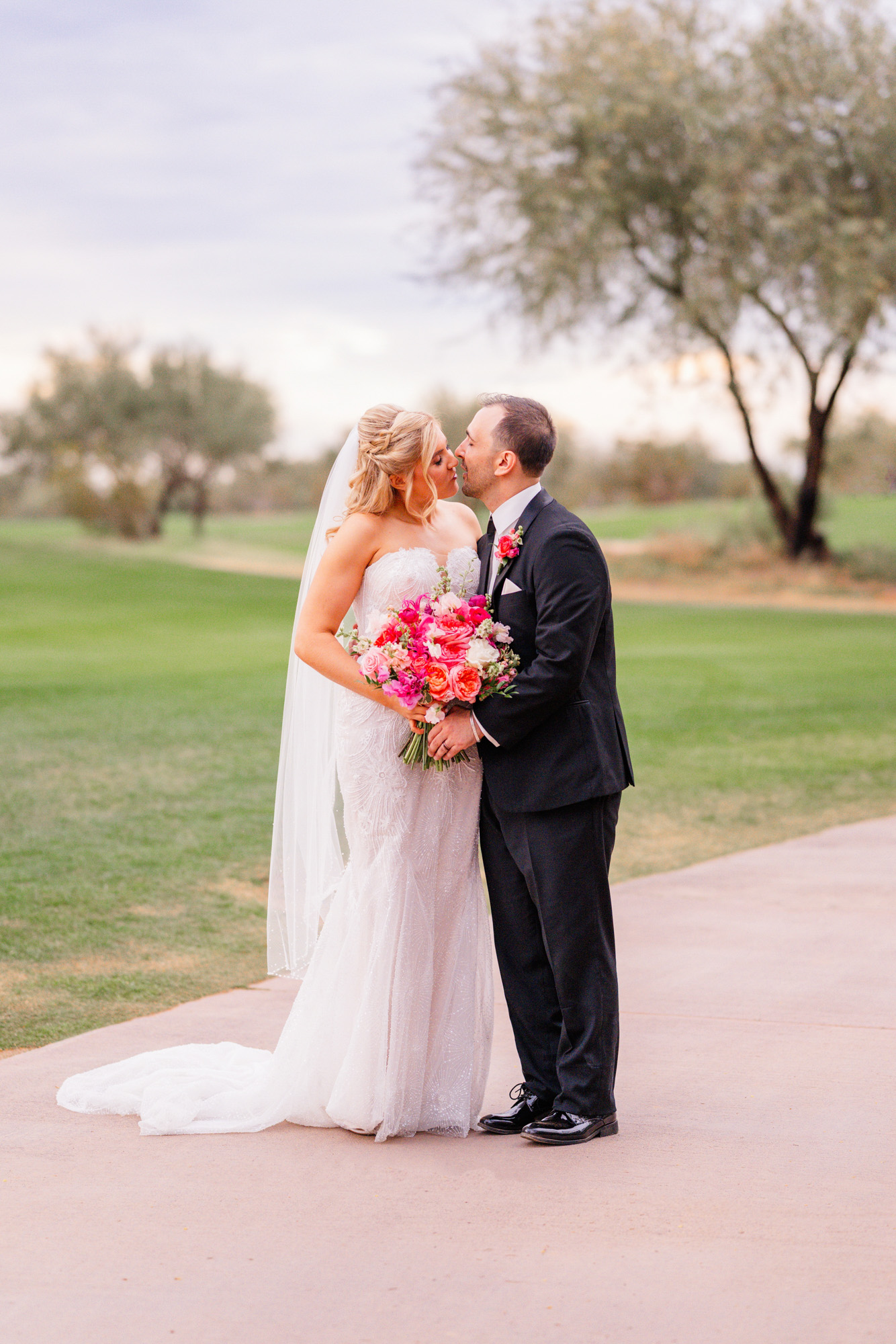 Bride and groom kissing on a golf course during wedding portraits.