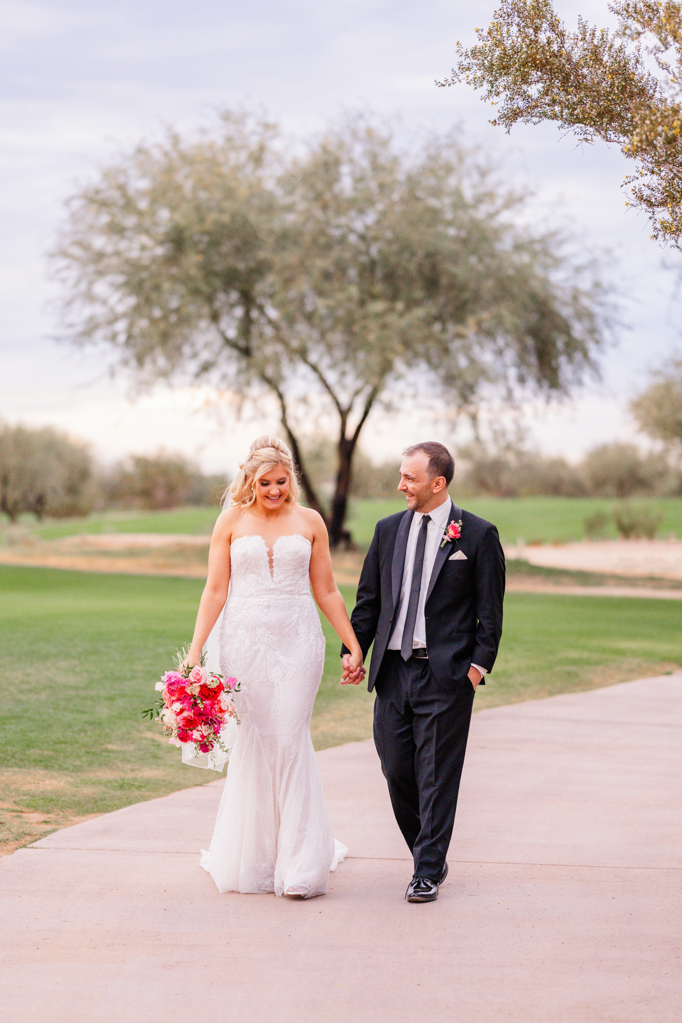 Bride and groom walking together and smiling during relaxed outdoor wedding portraits.