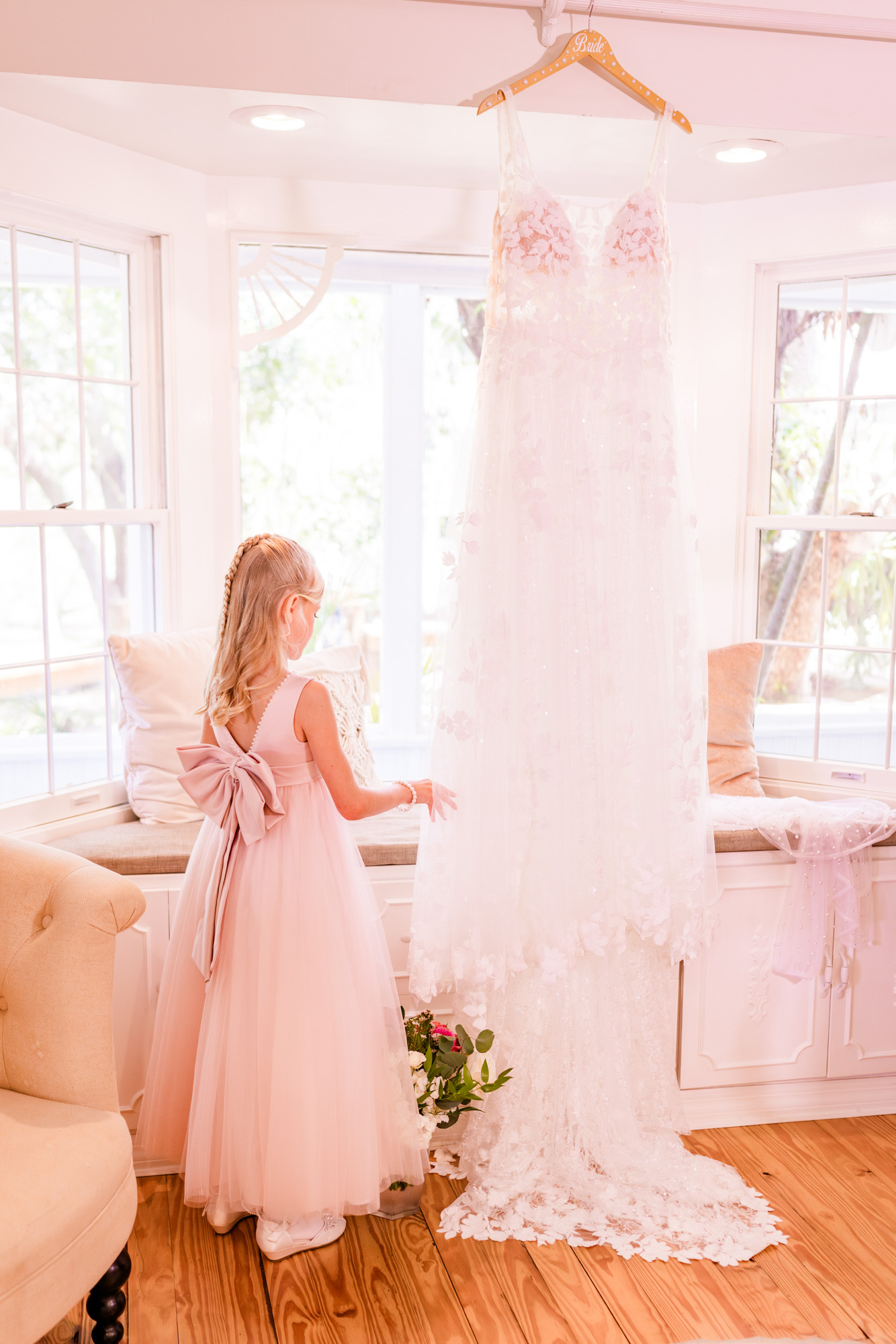Bride getting dressed with help from a family member while a flower girl watches.