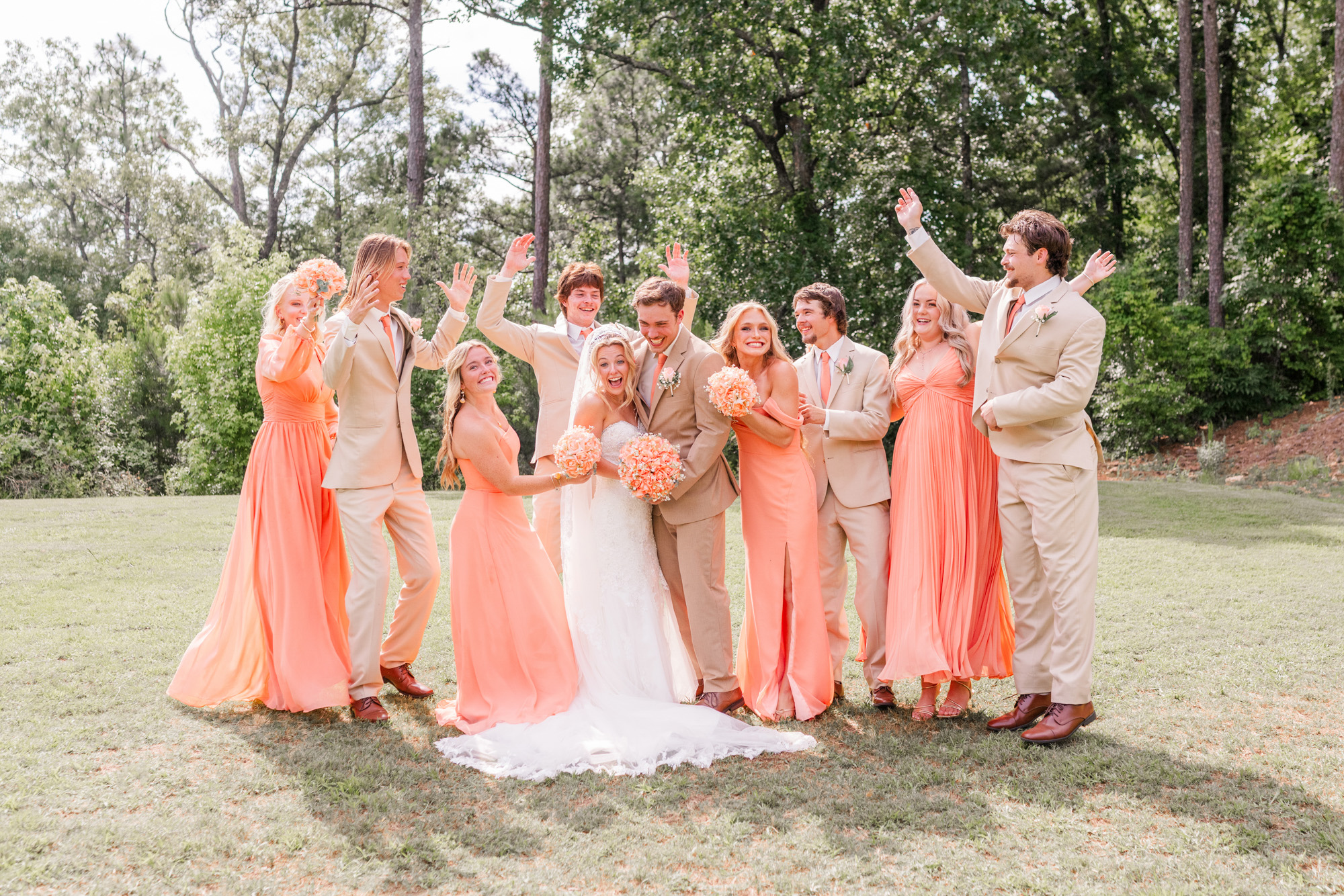 Bride and groom surrounded by their wedding party during a joyful group portrait.