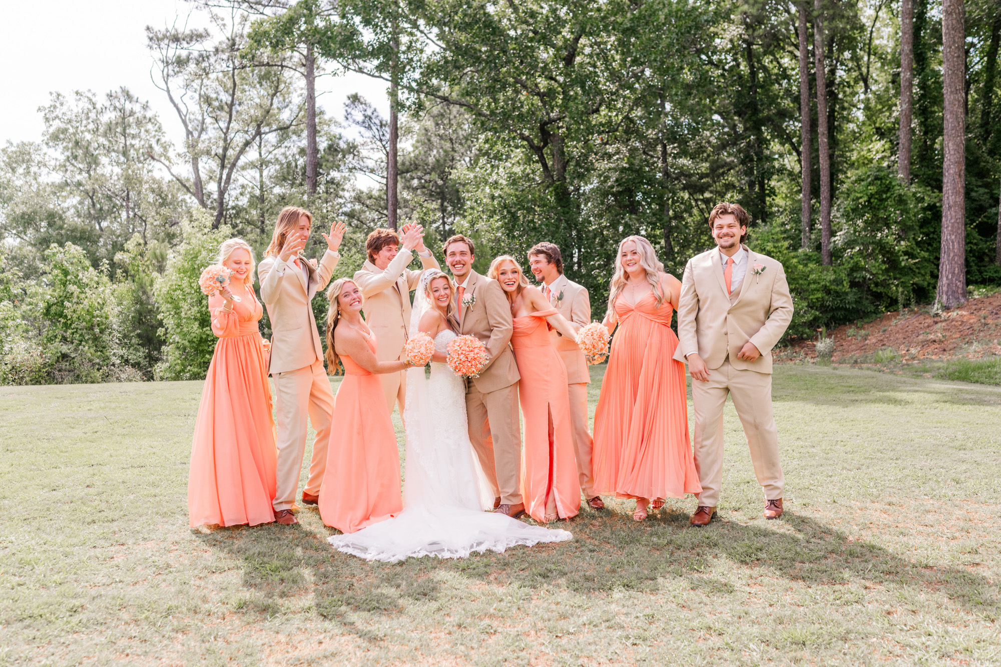 Bride and groom laughing with bridesmaids and groomsmen during wedding party photos.