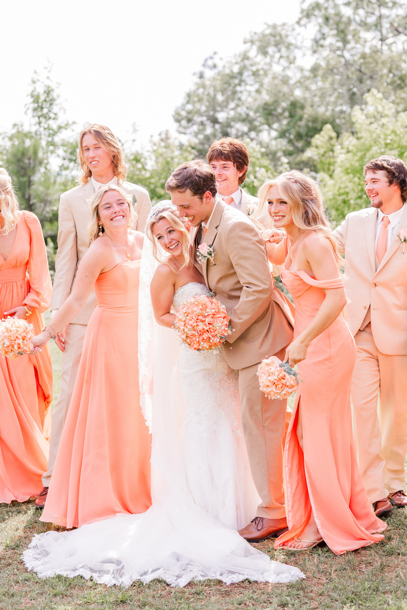 Bride and groom laughing together with friends during a candid wedding party portrait.
