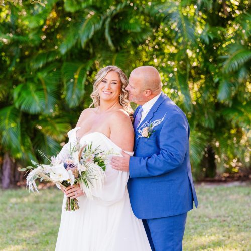 Couple hugging in front of foliage at their Treehouse wedding in Vero Beach, Florida