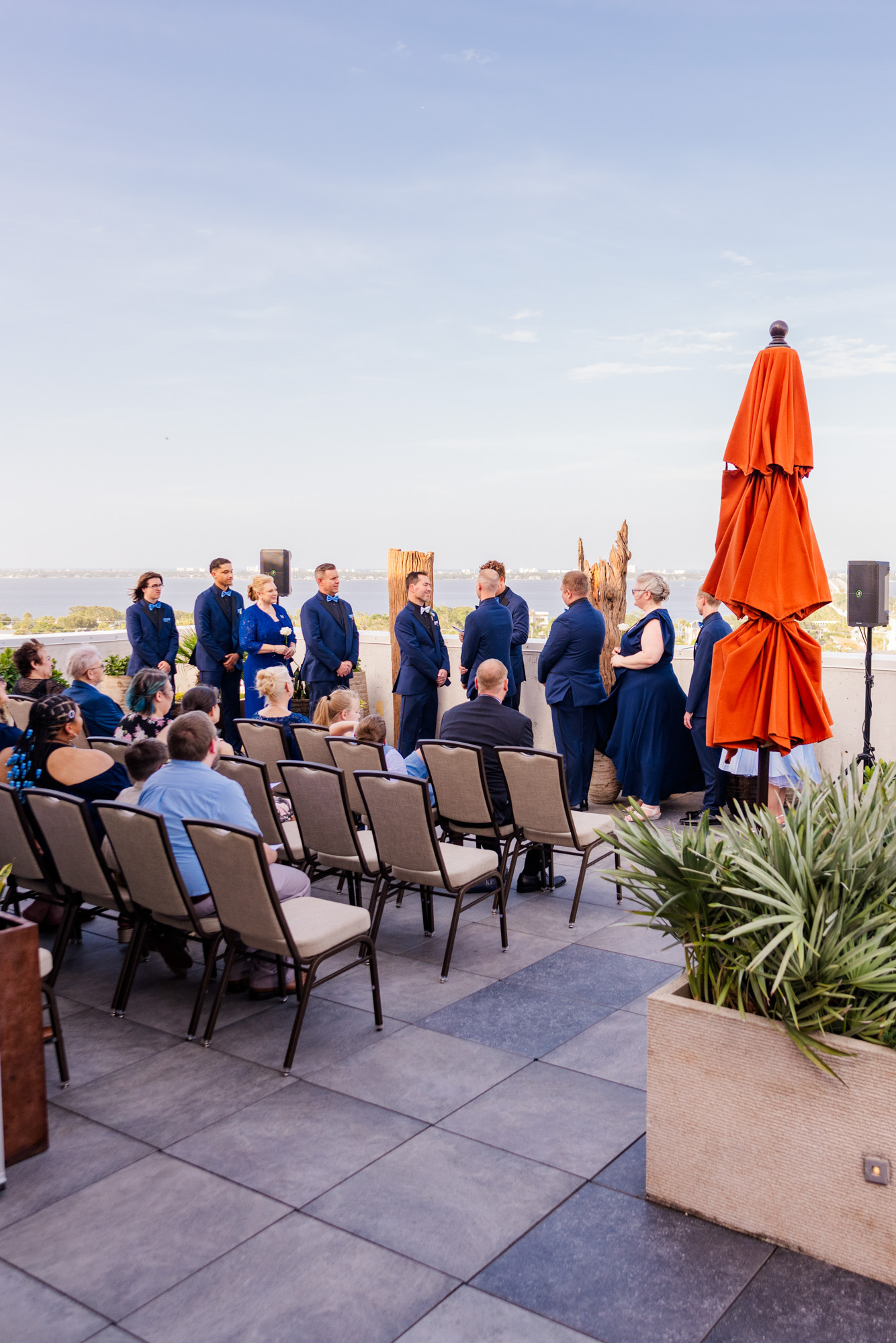 Two grooms exchanging vows during an outdoor rooftop wedding ceremony.