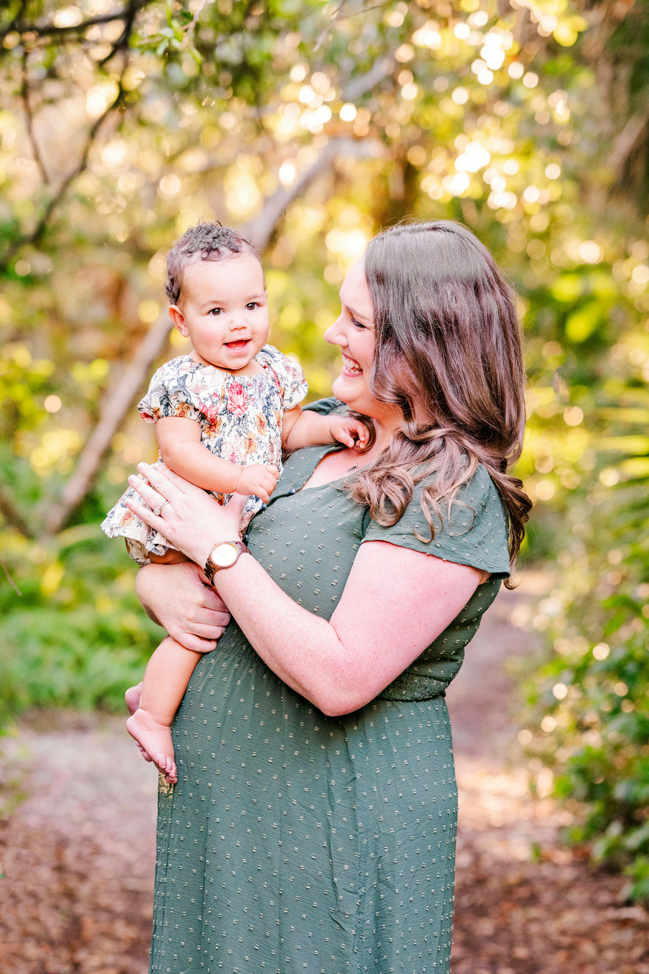 Mother holding her baby and smiling during a garden family portrait in Melbourne, Florida.