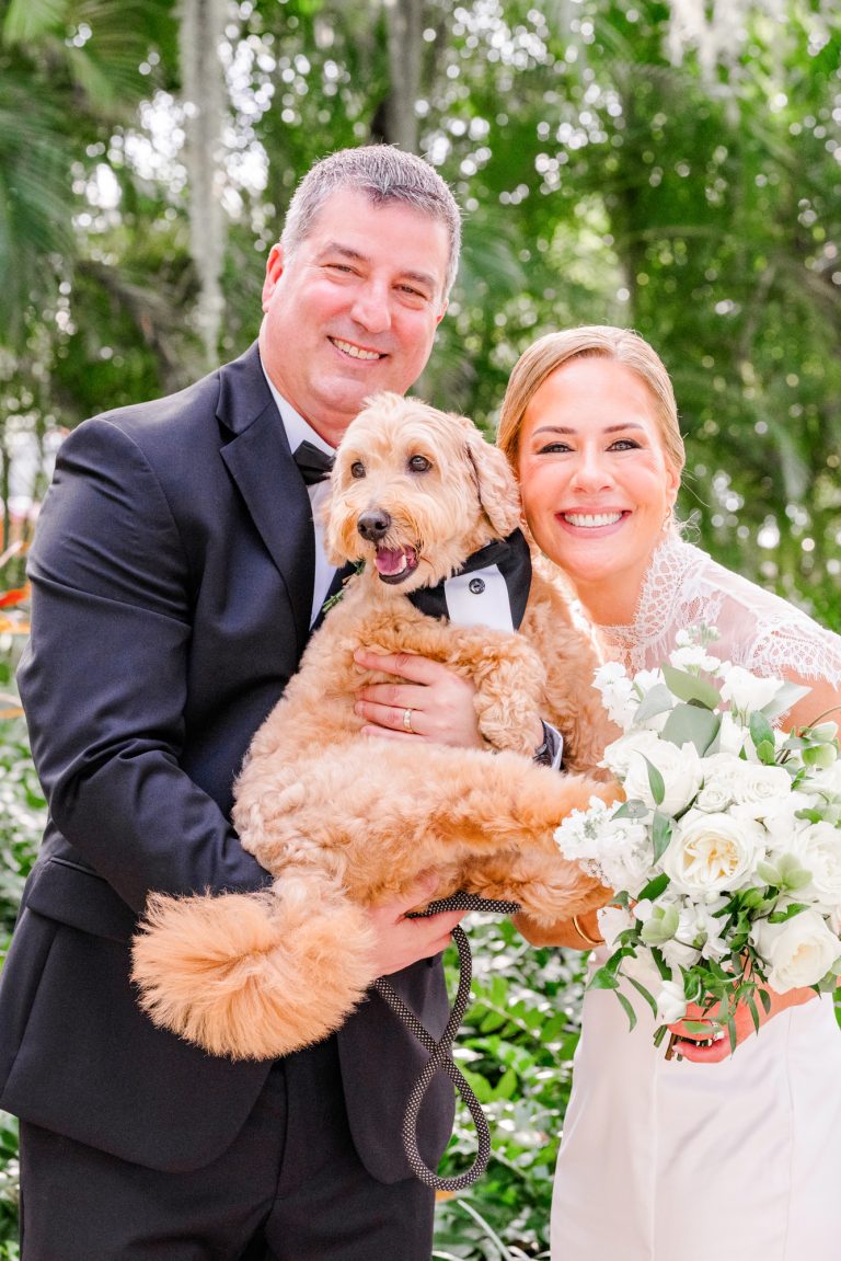 Couple holding their dog who has a bow tie on after their Melbourne Florida elopement