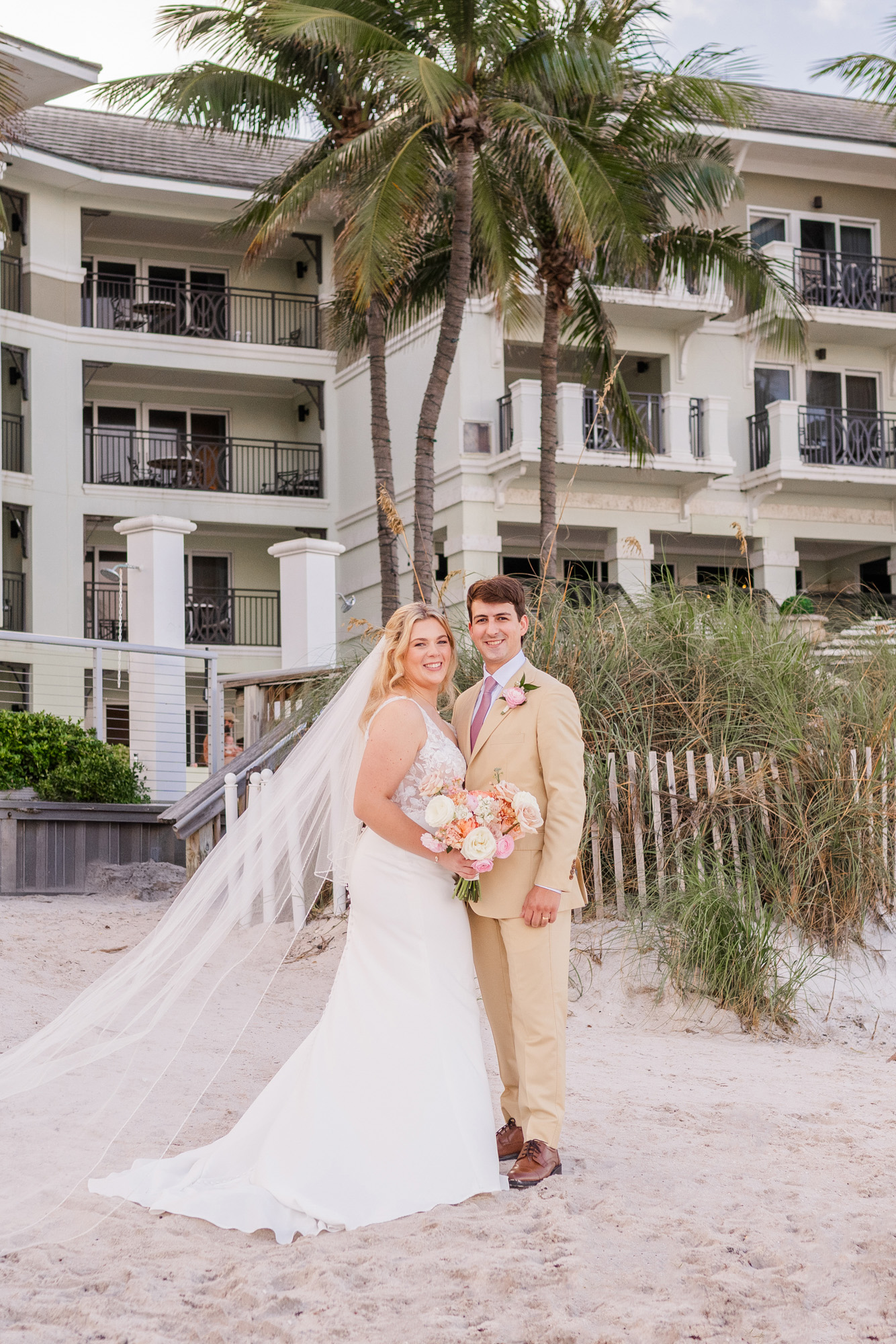 Bride and groom posing on the beach with Vero Beach Hotel & Spa in the background.