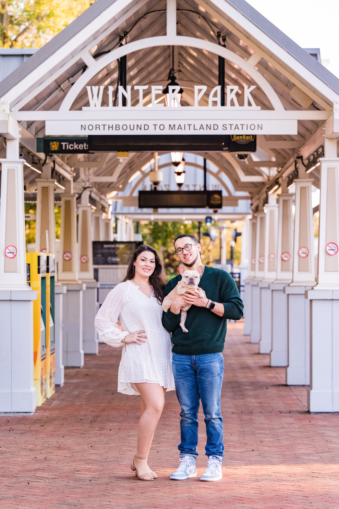 couple standing under the Winter Park sign at the train station