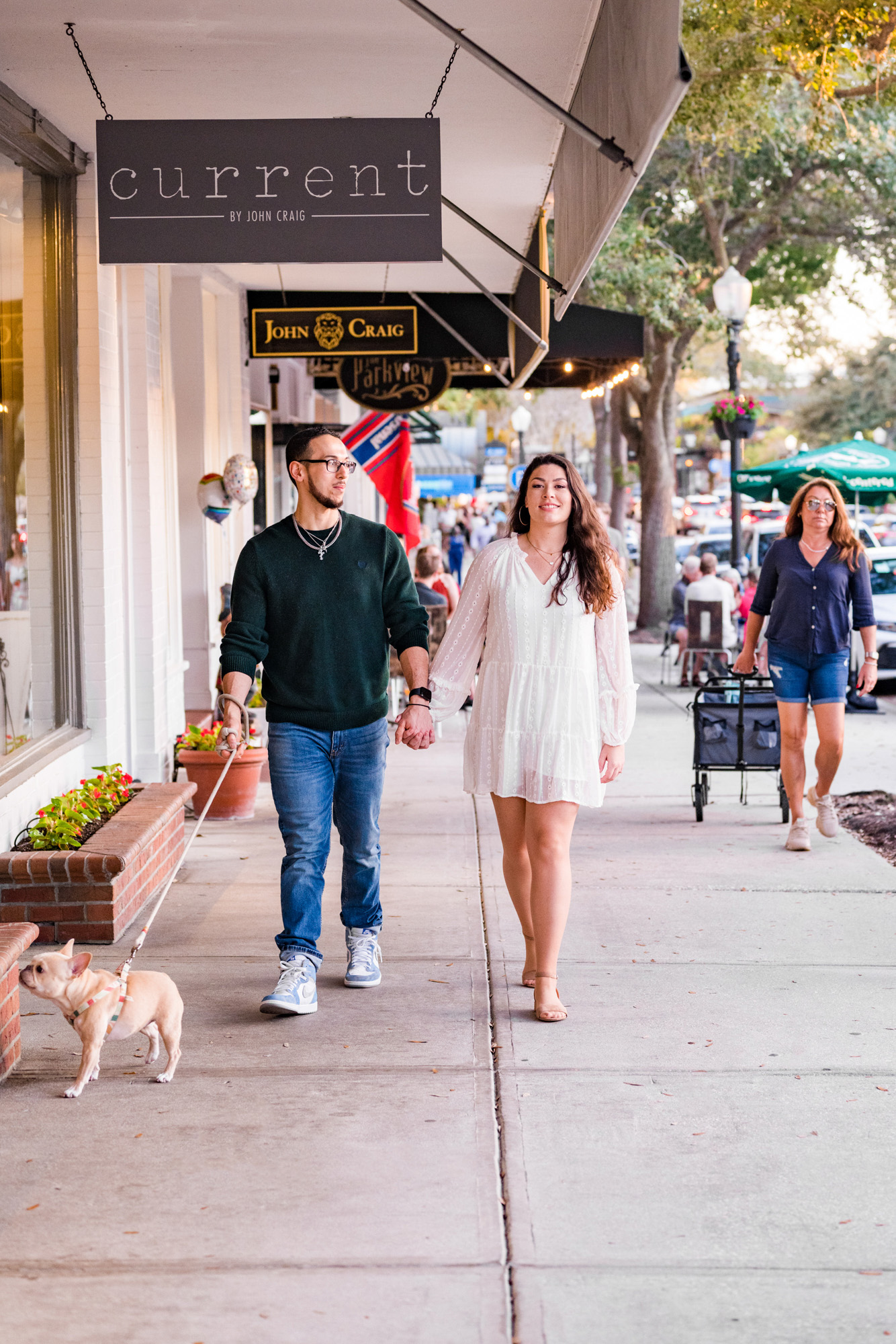 Couple walking with their dog down Park Ave in Winter Park during their engagement session
