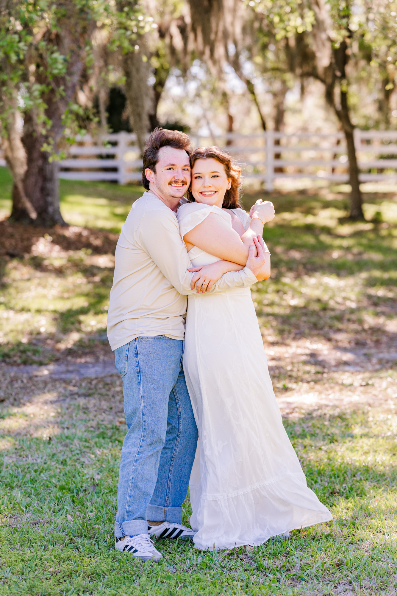 Man hugging woman from behind under the oak trees during their engagement session
