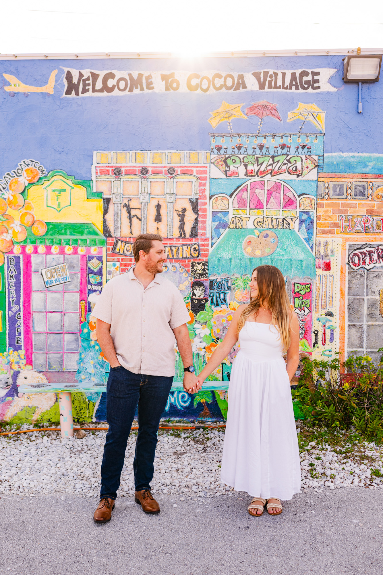 Couple holding hands in front of mural in Cocoa village