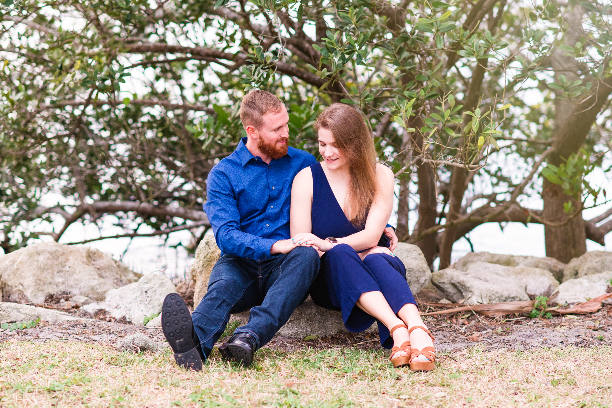 couple sitting near the river looking at her engagement ring at Rykeman Park in Melbourne Beach