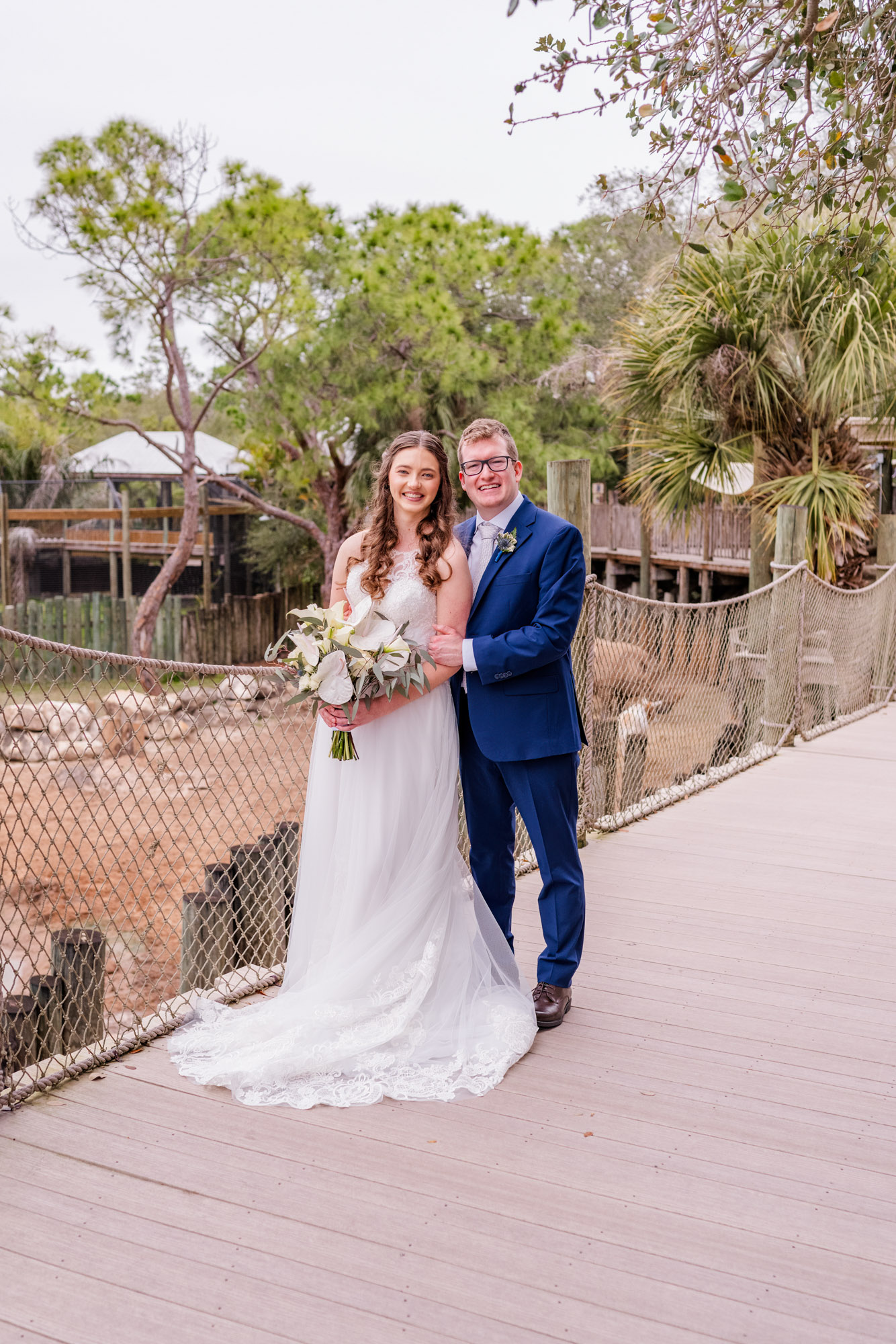 man behind woman standing on the bridge at the Brevard Zoo.
