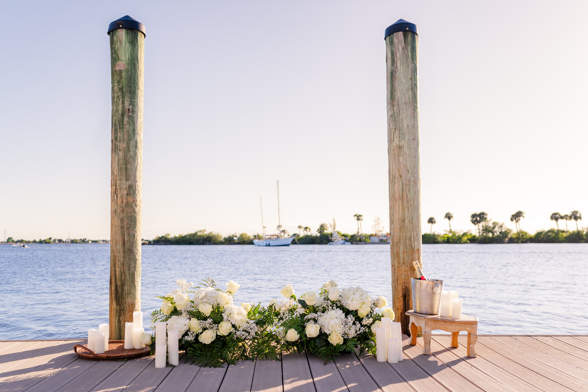 Romantic waterfront proposal setup at Eau Gallie Yacht Club in Melbourne, Florida, featuring white florals, candles, and champagne.